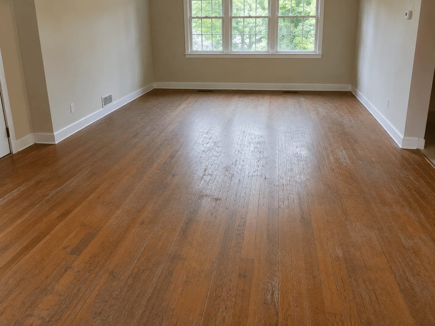 Bedroom with dull, worn hardwood floor before refinishing